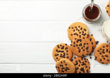 Zusammensetzung mit Chip Cookies, Milch und Karamell auf weißem Holztisch Stockfoto