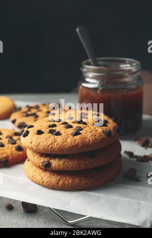 Zusammensetzung mit Chip Cookies und Karamell auf grauem Tisch Stockfoto