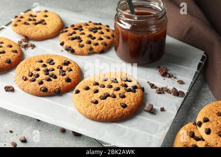 Zusammensetzung mit Chip Cookies und Karamell auf grauem Tisch Stockfoto