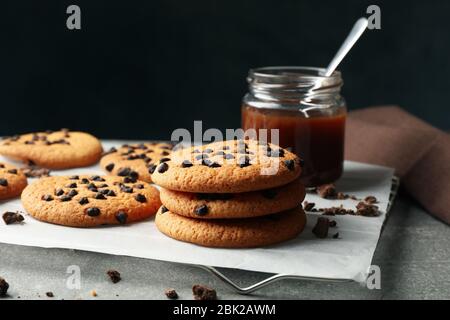 Zusammensetzung mit Chip Cookies und Karamell auf grauem Tisch Stockfoto