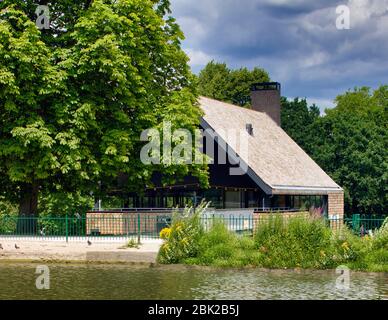 Blick über den See mit Bootstouren. Crystal Palace Park Cafe, Crystal Palace, Großbritannien. Architekt: Chris Dyson Architects, 2020. Stockfoto