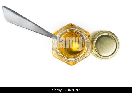 Teelöffel in einem sechseckigen Honigglas auf weiß isoliert. Draufsicht. Stockfoto