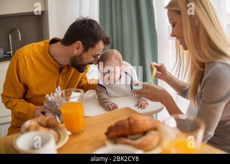Eltern füttern Baby zusammen.Vater und Mutter füttern ihren niedlichen Babyjungen. Stockfoto