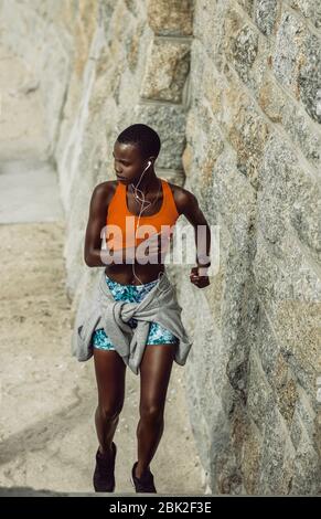 Gesunde Frau läuft nach oben. Afrikanische Frau während des Routine-Fitness-Training am Morgen. Stockfoto