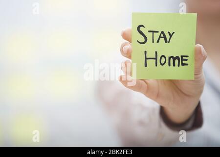 Handgehaltener Haftnotiz mit Stay Home-Text Stockfoto