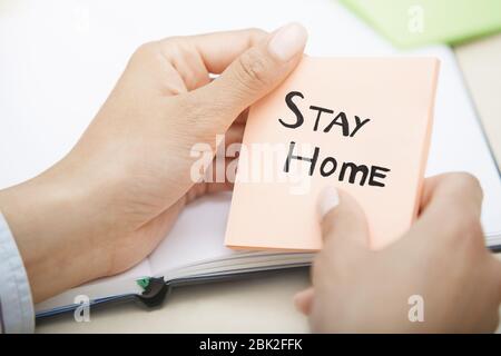 Hände mit pinkfarbenem Haftnotiz und Stay Home-Text Stockfoto