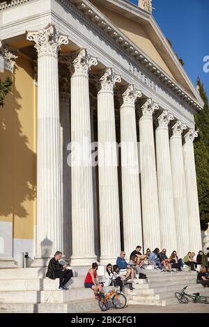 Menschen vor dem Zappeion Gebäude in den Nationalen Gärten von Athen, Griechenland. Genießen Sie die Sonne trotz Coronavirus-Epidemie Stockfoto