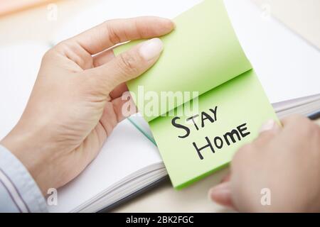 Hände halten Haftnotiz mit Stay Home-Text Stockfoto