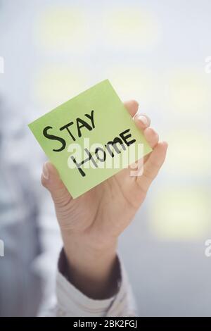 Hände halten Haftnotiz mit Stay Home-Text Stockfoto