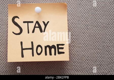 Haftnotiz mit Stay Home-Text auf einem Pinnwand Stockfoto