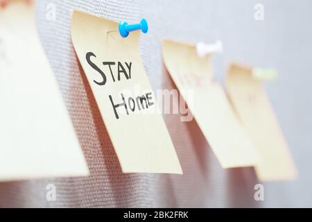 Haftnotiz mit Stay Home-Text auf einem Pinnwand Stockfoto