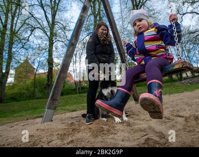 01. Mai 2020, Mecklenburg-Vorpommern, Grevesmühlen: Die zweijährige Elli-Marie schwingt neben ihrer Mutter Ann-Karthrin Wulff auf dem Spielplatz auf der Bürgerwiese. Pünktlich zum 1. Mai hat die Landesregierung Mecklenburg-Vorpommerns die Spielplätze nach wochenlanger Schließung im Rahmen der Corona-Schutzmaßnahmen wieder eröffnet. Foto: Jens Büttner/dpa-Zentralbild/dpa Stockfoto