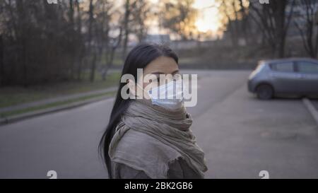 Asiatische Frau in Medical Maske steht auf Sonnenuntergang Hintergrund Stockfoto