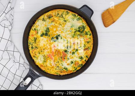 Hausgemachte Frittata oder Omelette mit Mischung aus Gemüse in Eisen Pfanne auf weißem Tisch, Stockfoto