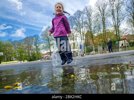 01. Mai 2020, Mecklenburg-Vorpommern, Grevesmühlen: Die vierjährige Isabel springt auf dem Spielplatz auf der Bürgerwiese in eine Pfütze. Pünktlich zum 1. Mai hat die Landesregierung Mecklenburg-Vorpommerns die Spielplätze nach wochenlanger Schließung im Rahmen der Corona-Schutzmaßnahmen wieder eröffnet. Foto: Jens Büttner/dpa-Zentralbild/dpa - ACHTUNG: Redaktionell, einmalige Nutzung nur im Zusammenhang mit der Berichterstattung über die Eröffnung von Spielplätzen und nur, wenn der oben genannte Kredit vollständig referenziert ist Stockfoto