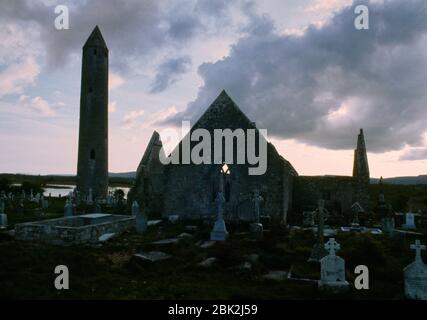 Blick auf den runden Turm neben der teilweise zerstörten Kathedrale in Kilmacduagh, Co Galway, Republik Irland: Er ist über 30 m hoch. Stockfoto