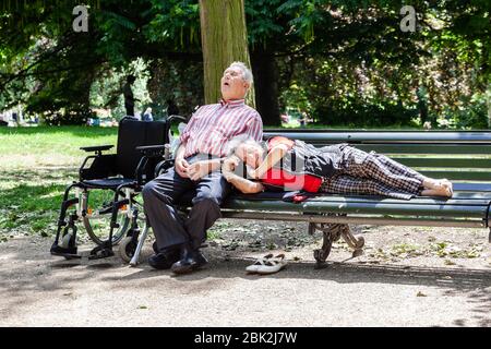 Ältere Paare, die sich auf Parkbank ausruhen, London, England, Großbritannien. Stockfoto