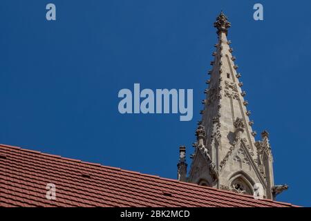 Diagonale Linie eines neuen roten Daches. Spitze eines schlanken Steinturms der St. Clarissine Kirche und Kloster. Gotischer Stil, viele kunstvolle Details. Strahlend blauer Himmel. B Stockfoto