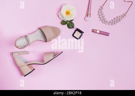 Komposition mit Damensandalen und Accessoires auf rosa Hintergrund. Stockfoto