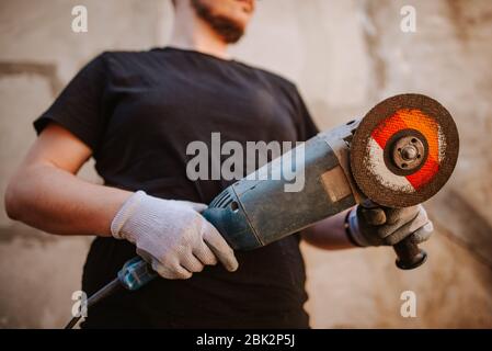 Ein junger Kaukasusmann hält eine Mühle in der Hand Stockfoto