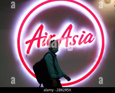 Bangkok, Thailand. Mai 2020. Ein Passagier geht während der COVID-19-Krise am Don Muang International Airport mit einer Gesichtsmaske an einem Air Asia Logo vorbei. Thai AirAsia und Thai Lion Air nahmen die Flüge auf Inlandsflügen wieder auf, nachdem der Flug aufgrund des Ausbruchs von Covid-19 vorübergehend unterbrochen wurde. Quelle: SOPA Images Limited/Alamy Live News Stockfoto