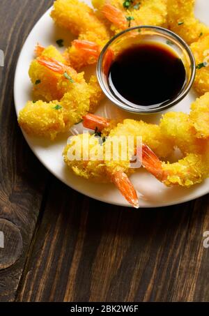 Nahaufnahme von frittierten panierten Garnelen auf dem Teller auf Holztisch. Stockfoto