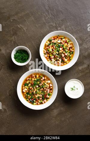 Traditionelle kalte russische Suppe Okroschka mit Wurst, Gemüse und Kvass über braunem Hintergrund. Leckeres Sommergericht zum Abendessen. Draufsicht, flacher Lay Stockfoto