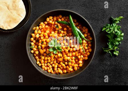 Knusprig geröstete Kichererbsen. Gericht im indischen Stil über schwarzem Stein Hintergrund. Vegetarisches veganes Food Konzept. Draufsicht, flaches Lay Stockfoto