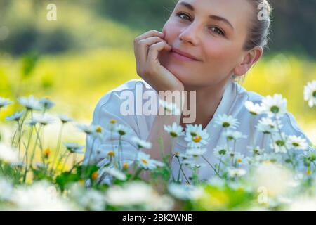 Porträt einer schönen jungen Frau mit Freude verbringen Zeit im Freien, genießen frische Gänseblümchen Blumen auf der Blumenwiese, frohe Frühlingsferien Stockfoto