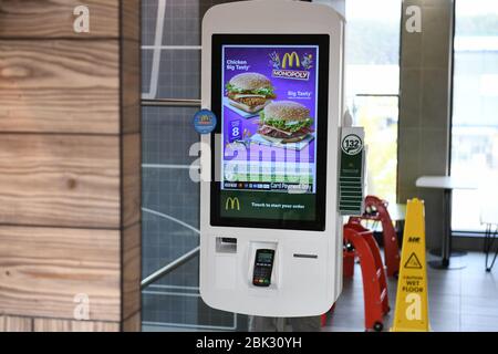 Self-Service-Interaktionsmöglichkeiten in einem typischen McDonalds Restaurant in Großbritannien. Die Abbildung zeigt zwei Burger auf dem farbenfrohen Menübildschirm Stockfoto