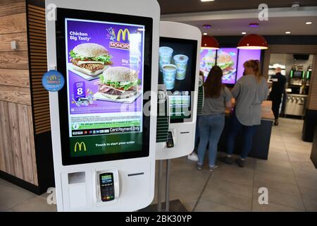 Self-Service-Interaktionsmöglichkeiten in einem typischen McDonalds Restaurant in Großbritannien. Die Abbildung zeigt zwei Burger auf dem farbenfrohen Menübildschirm Stockfoto