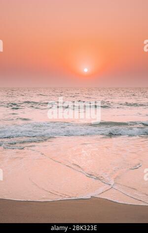 Sonnenuntergang Sonne Über Dem Meer. Natürlicher Sonnenaufgang Himmel Warme Farben Über Dem Meer. Meer Wasser Schaum Spritzer Waschen Sandstrand. Stockfoto