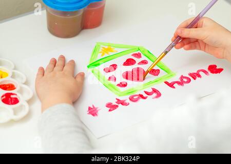 Kind zeichnet Herz im Haus auf weißem Blatt Papier mit Worten bleiben zu Hause. Stay Home Konzept. Stockfoto