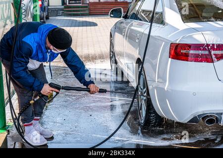 Kontaktlose Autowäsche mit Selbstbedienung. Junge Gelegenheitsmännchen waschen sein Auto Stockfoto