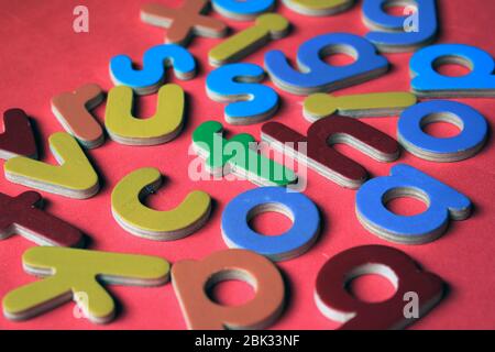 Englische Alphabete. Bunte hölzerne englische kleine Buchstaben auf einem rosa Hintergrund. Stockfoto