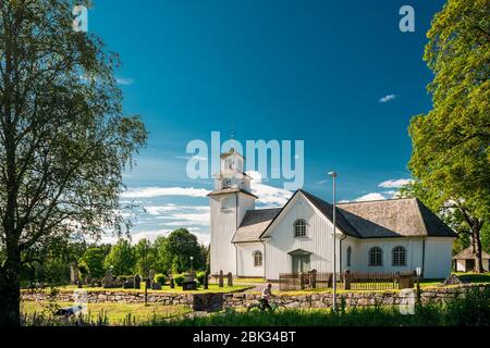 Tocksfors, Schweden - 26. Juni 2019: Mann, der in der Nähe der Tocksmarks Kirche im sonnigen Sommertag spazieren geht. Lokales Wahrzeichen. Stockfoto
