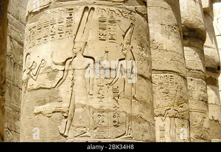 Touristen besuchen die Säulen am Karnak-Tempel in der monumentalen Stadt Theben in der Nähe von Luxor, Ägypten. Ägyptische Hieroglyphen schmücken die Wände des T Stockfoto