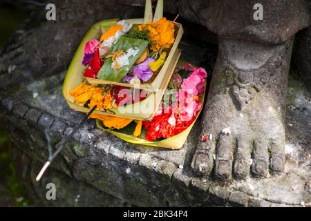 Canang Sari zu Füßen einer Statue, Ubud, Bali, Indonesien Stockfoto