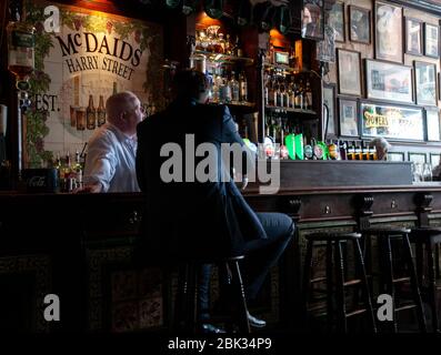 Gäste und Gäste im Gespräch an der Bar im McDaids Pub in der Harry Street in Dublin, Irland. Stockfoto