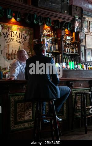 Gäste und Gäste im Gespräch an der Bar im McDaids Pub in der Harry Street in Dublin, Irland. Stockfoto