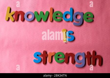 Wissen ist Stärke. Wissen ist Kraft, die mit dem englischen Holzalphabet an die Wand geschrieben wird. Stockfoto