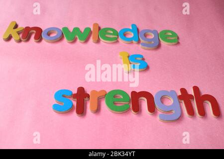 Wissen ist Stärke. Wissen ist Kraft, die mit dem englischen Holzalphabet an die Wand geschrieben wird. Stockfoto