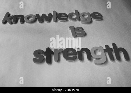 Wissen ist Stärke. Wissen ist Kraft, die mit dem englischen Holzalphabet an die Wand geschrieben wird. Stockfoto