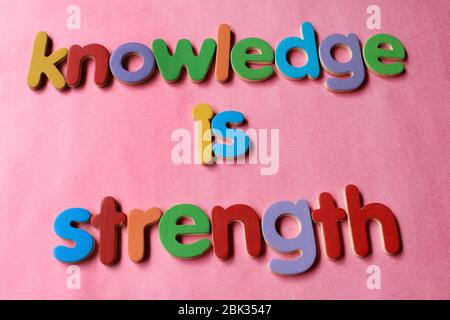 Wissen ist Stärke. Wissen ist Kraft, die mit dem englischen Holzalphabet an die Wand geschrieben wird. Stockfoto