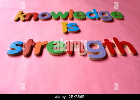 Wissen ist Stärke. Wissen ist Kraft, die mit dem englischen Holzalphabet an die Wand geschrieben wird. Stockfoto
