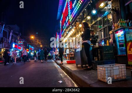 Personal im Restaurant buhlen um Kunden in den frühen Abendstunden auf Shouning Straße Lebensmittel-Straße in Shanghai Stockfoto