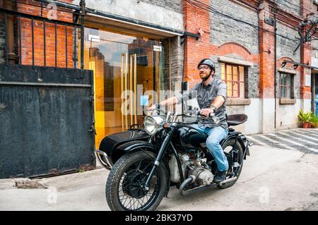 Shanghai Insider Arthur Humeau auf seinem Changjiang 750 Motorrad seitenwagen vor ArtCN, in der ehemaligen Foh singen Mühle Gebäude in Shanghai ins Stockfoto
