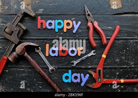 Happy Labor Day Text in mehrfarbig auf Holzhintergrund mit Bau Reparatur-Tools. Schild „Labor Day Concept“. Stockfoto