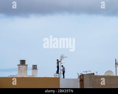 Männer auf einem Dach, die während covi-19 eine Antenne aufstellen Stockfoto