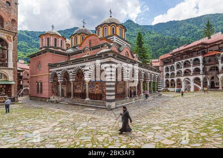 orthodoxer Mönch vor dem rila-Kloster in bulgarien, der über den Hof läuft Stockfoto